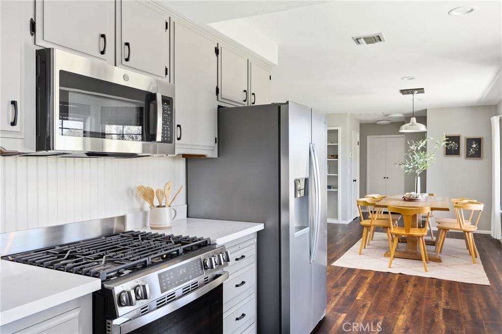 6030 Portola Road Atascadero, CA 93422 - Photo 14 of 44 a kitchen with stainless steel appliances granite countertop a stove a refrigerator and a dining table with wooden floor