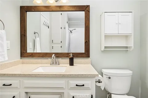 a bathroom with a granite countertop sink and a toilet