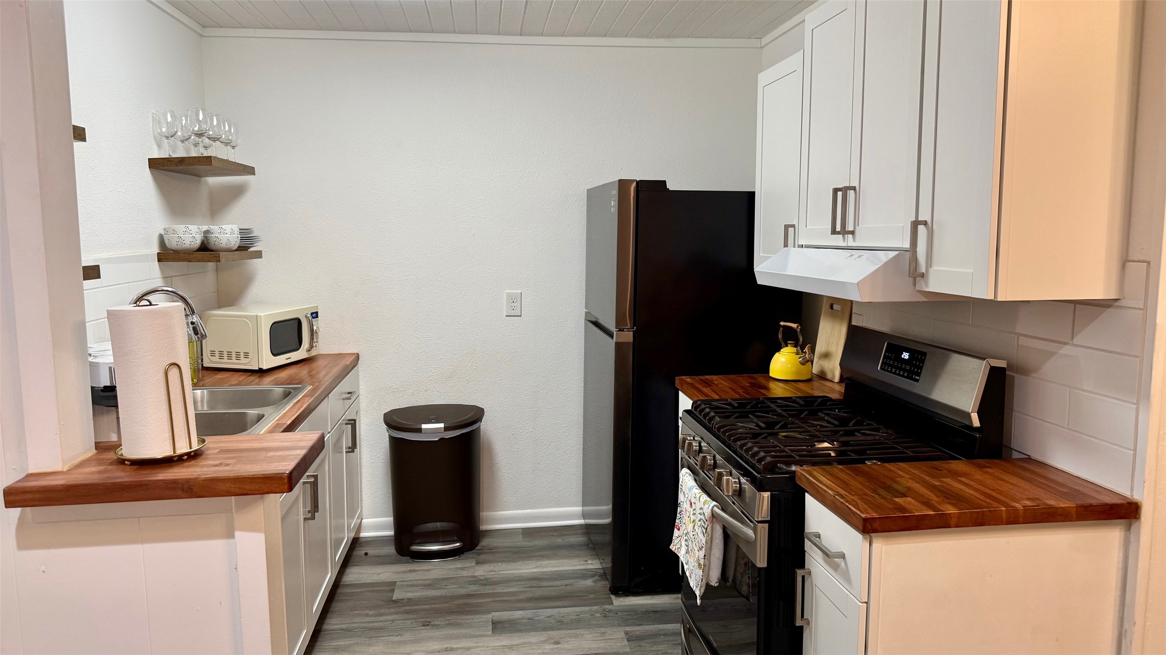 1802 East University Avenue, Unit A Georgetown, TX 78626 - Photo 8 of 23 Kitchen with butcher block countertops, gas stove, open shelves, white cabinetry, and white microwave