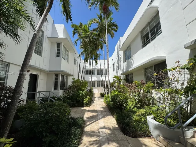 a view of multi story residential apartment building with a yard and potted plants