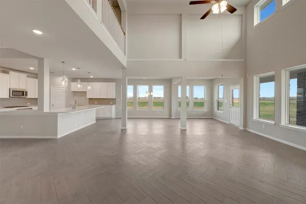 a view of an empty room with wooden floor and a kitchen