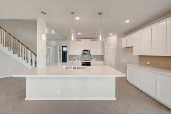 a large white kitchen with a large counter top and stainless steel appliances