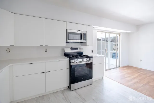 a kitchen with cabinets stainless steel appliances and wooden floor