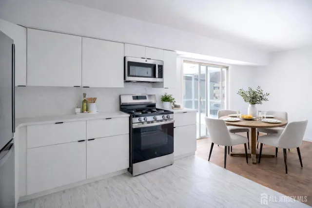 a kitchen with stainless steel appliances a white table chairs and a wooden floor