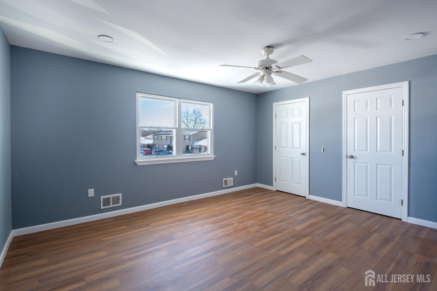 72 Haven Drive, Unit D Matawan, NJ 07747 - Photo 7 of 12 an empty room with wooden floor chandelier fan and windows