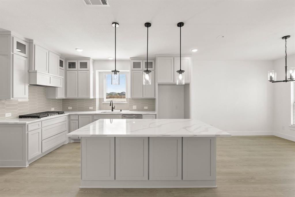 1617 Whisperwood Way Midlothian, TX 76065 - Photo 23 of 40 a large kitchen with granite countertop a stove a sink and white cabinets