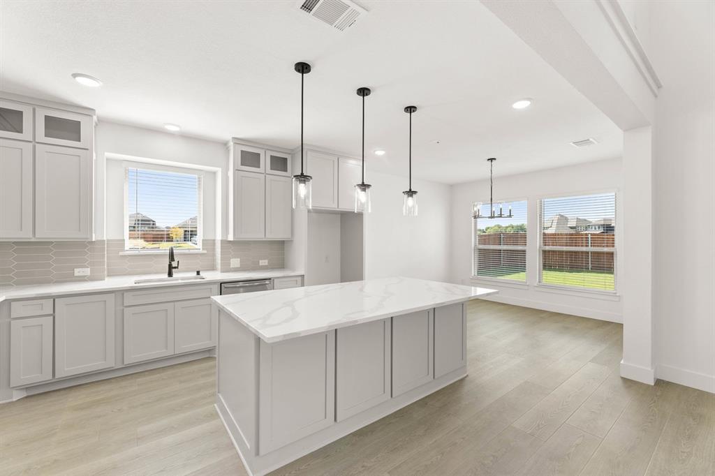 1617 Whisperwood Way Midlothian, TX 76065 - Photo 24 of 40 a kitchen with a sink a stove a refrigerator and white cabinets with wooden floor