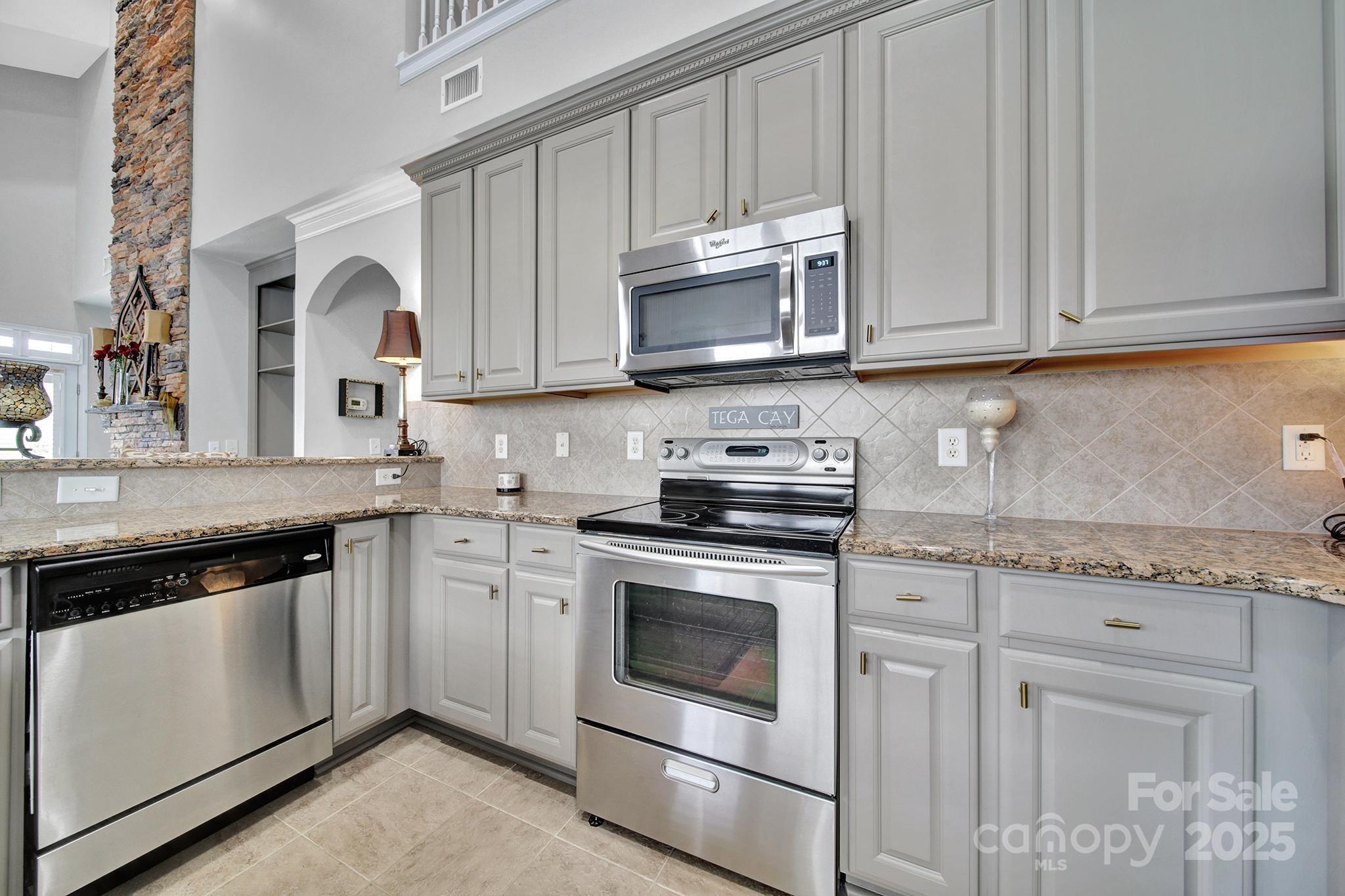 314 Wave Crest Drive Tega Cay, SC 29708 - Photo 7 of 39 a kitchen with granite countertop white cabinets and stainless steel appliances
