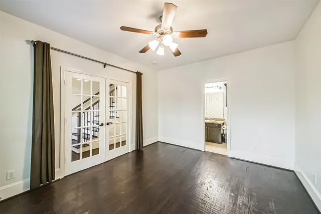an empty room with wooden floor chandelier fan and windows