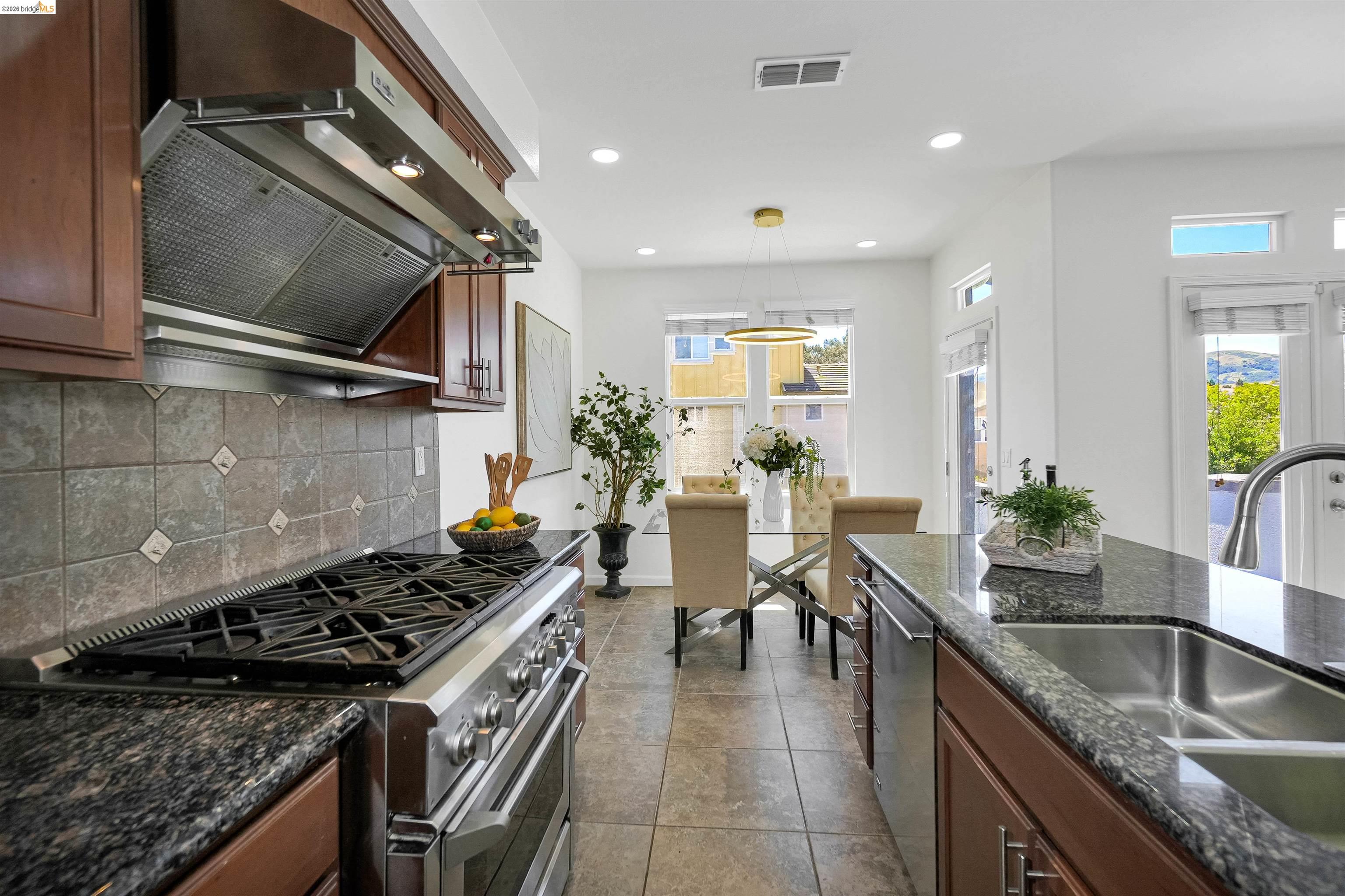449 Constantine Court San Ramon, CA 94583 - Photo 23 of 63 Gourmet kitchen featuring a professional-grade gas range, stainless steel range hood, stone tile backsplash, granite countertops, and rich wood cabinetry