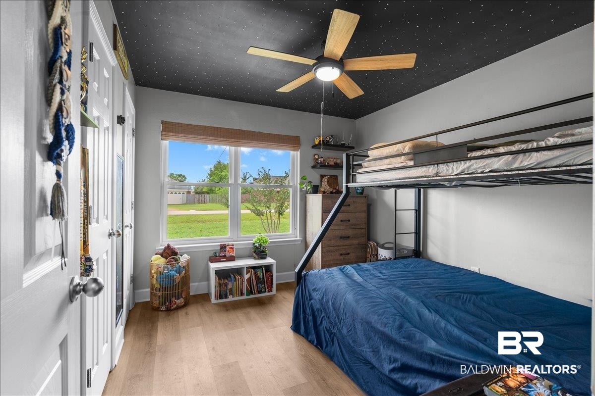 8952 Sherman Road Foley, AL 36535 - Photo 33 of 41 Bedroom featuring wood-finish flooring, a black star-patterned ceiling, and a ceiling fan with wood-finish blades