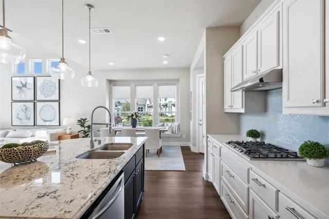 a kitchen with granite countertop a sink a stove and cabinets
