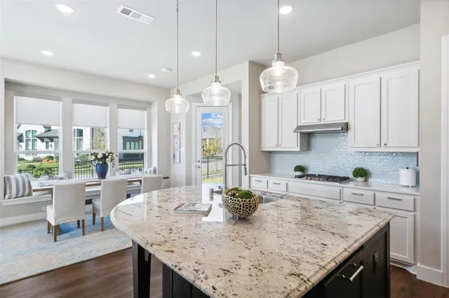 a kitchen with granite countertop a table chairs and wooden floor