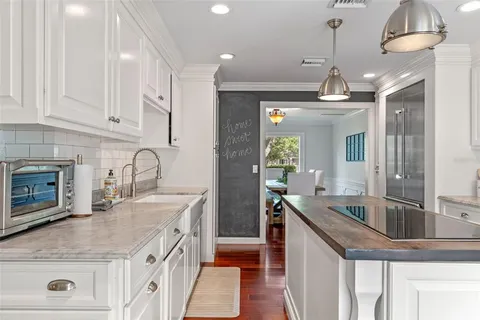 a kitchen with stainless steel appliances granite countertop a stove top oven a sink dishwasher and a refrigerator with wooden floor