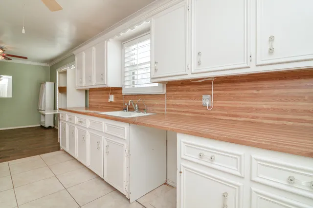 an empty room with wooden floor chandelier fan and windows