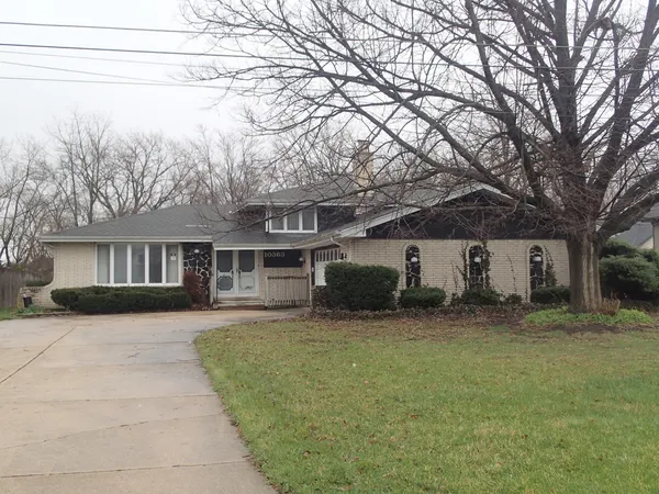 a front view of house with yard and trees in the background