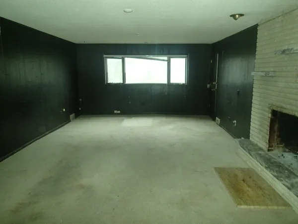 a view of an empty room with a fireplace and a window