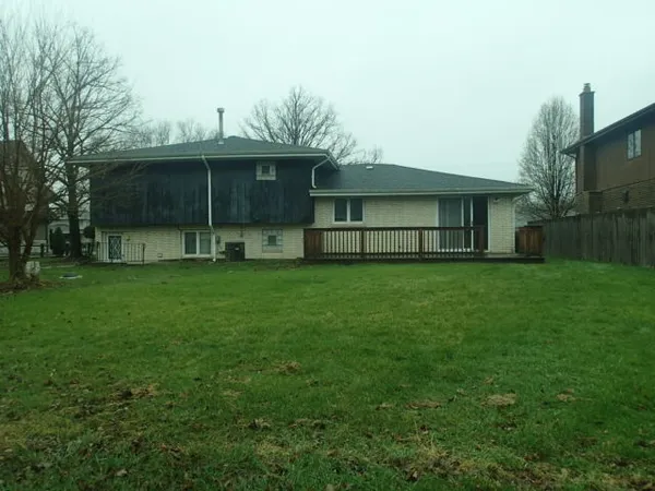 a view of a house with a yard and a large tree
