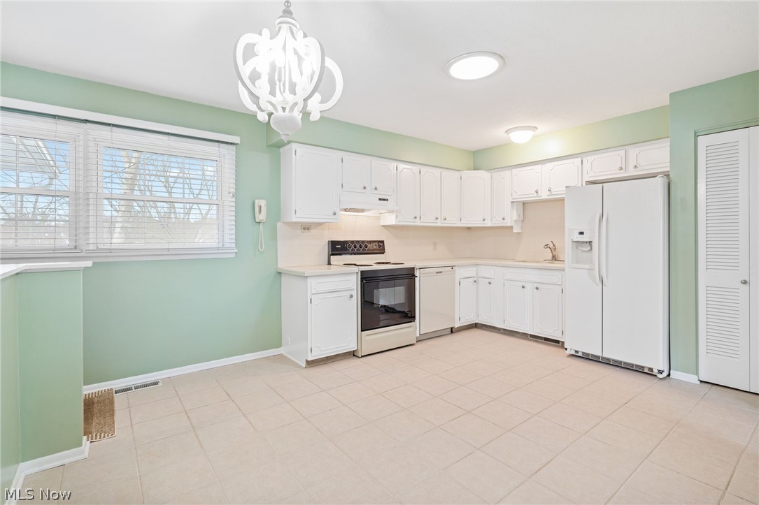 271 Manor Avenue Northwest Canton, OH 44708 - Photo 13 of 26 Kitchen featuring white appliances, light countertops, white cabinets, a chandelier, and light tile patterned flooring