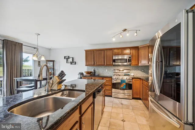 a kitchen with stainless steel appliances granite countertop a sink stove and refrigerator
