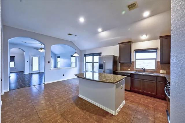 a kitchen with granite countertop stainless steel appliances stove top oven and cabinets