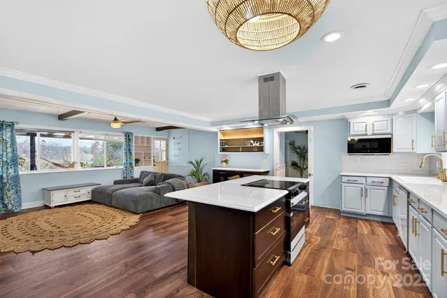 a large kitchen with stainless steel appliances a stove a sink dishwasher and a fireplace with wooden floor