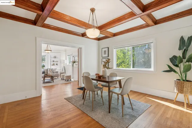 a dining room with wooden floor a chandelier a wooden table and chairs