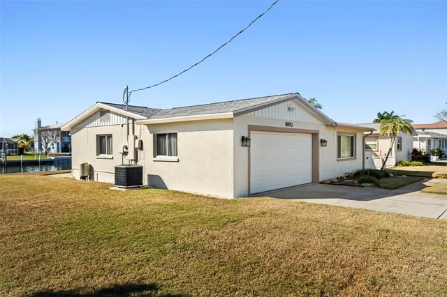 a view of white house with a big yard and large trees