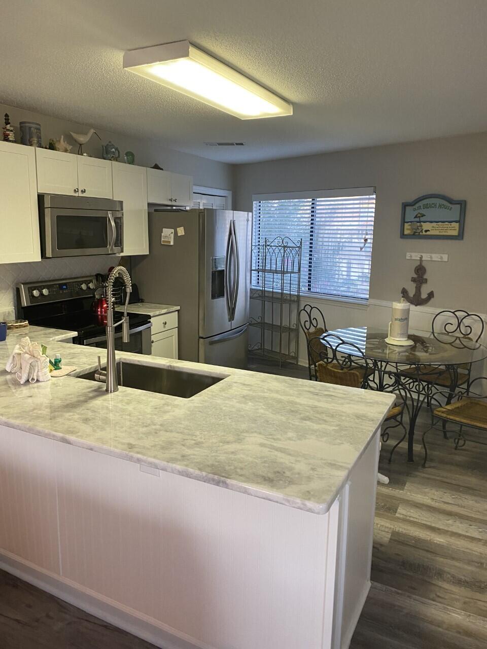 285 Payne Street, Unit 4B Miramar Beach, FL 32550 - Photo 4 of 12 a kitchen with stainless steel appliances kitchen island granite countertop a sink and cabinets
