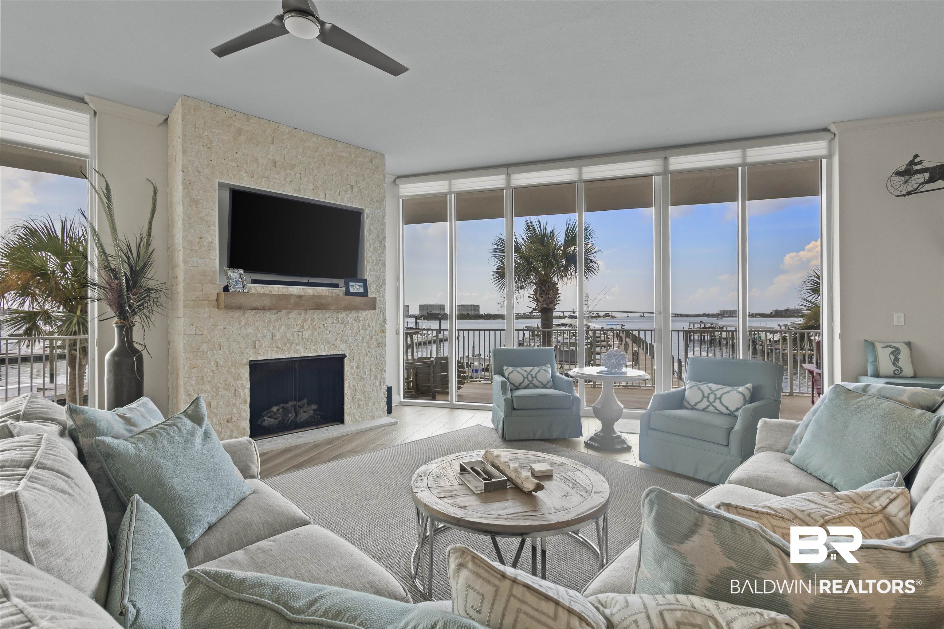 27800 Canal Road, Unit 120 Orange Beach, AL 36561 - Photo 3 of 68 Living room with a stone fireplace, a wealth of natural light, expansive windows, and ceiling fan