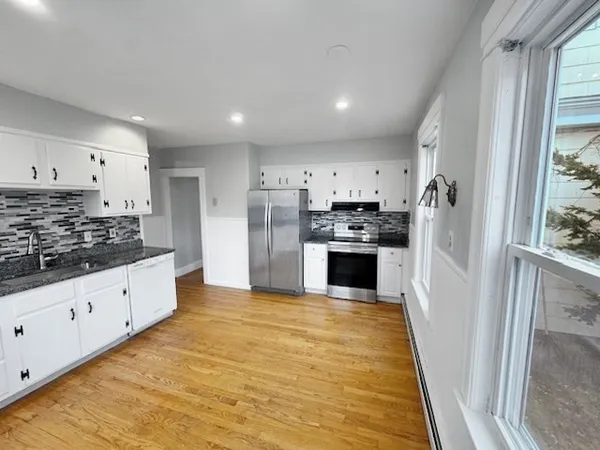 a large kitchen with stainless steel appliances kitchen island granite countertop a refrigerator and a stove top oven