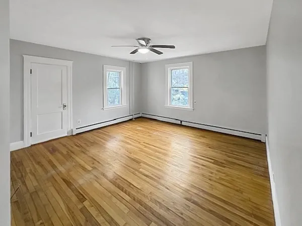 a view of empty room with wooden floor and fan