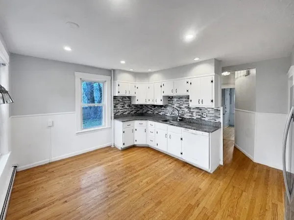 a kitchen with stainless steel appliances white cabinets and wooden floors