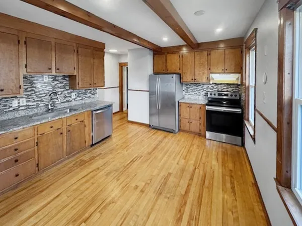 a kitchen with stainless steel appliances granite countertop a refrigerator a stove and a sink