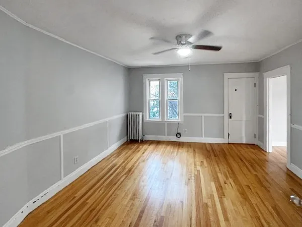 a view of an empty room with wooden floor and a window