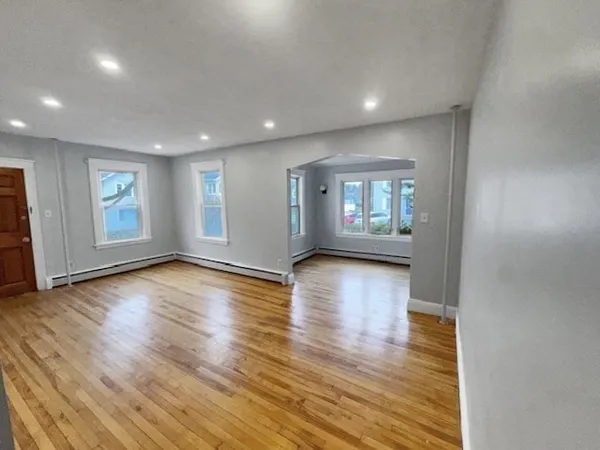 an empty room with wooden floor and windows