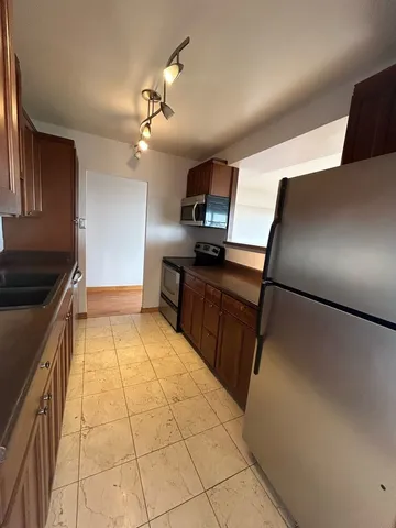 a kitchen with granite countertop a refrigerator and a stove top oven