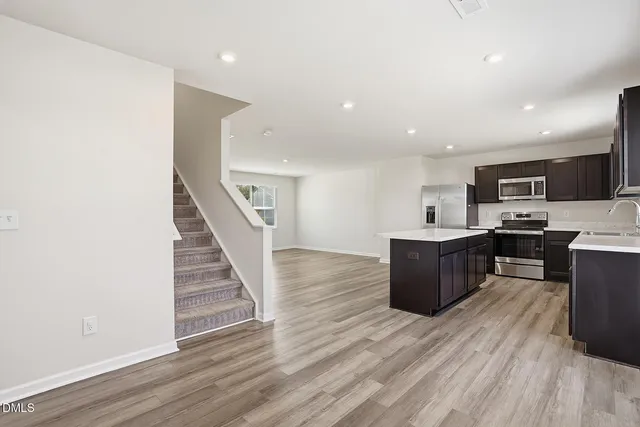 a large kitchen with stainless steel appliances wooden floors and wooden cabinets