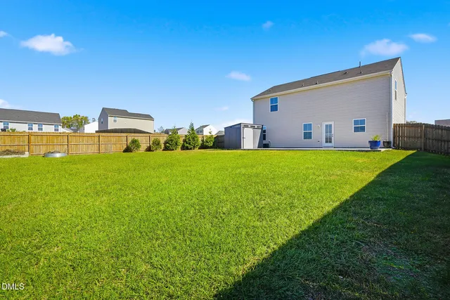 a view of a house with a yard and a large tree