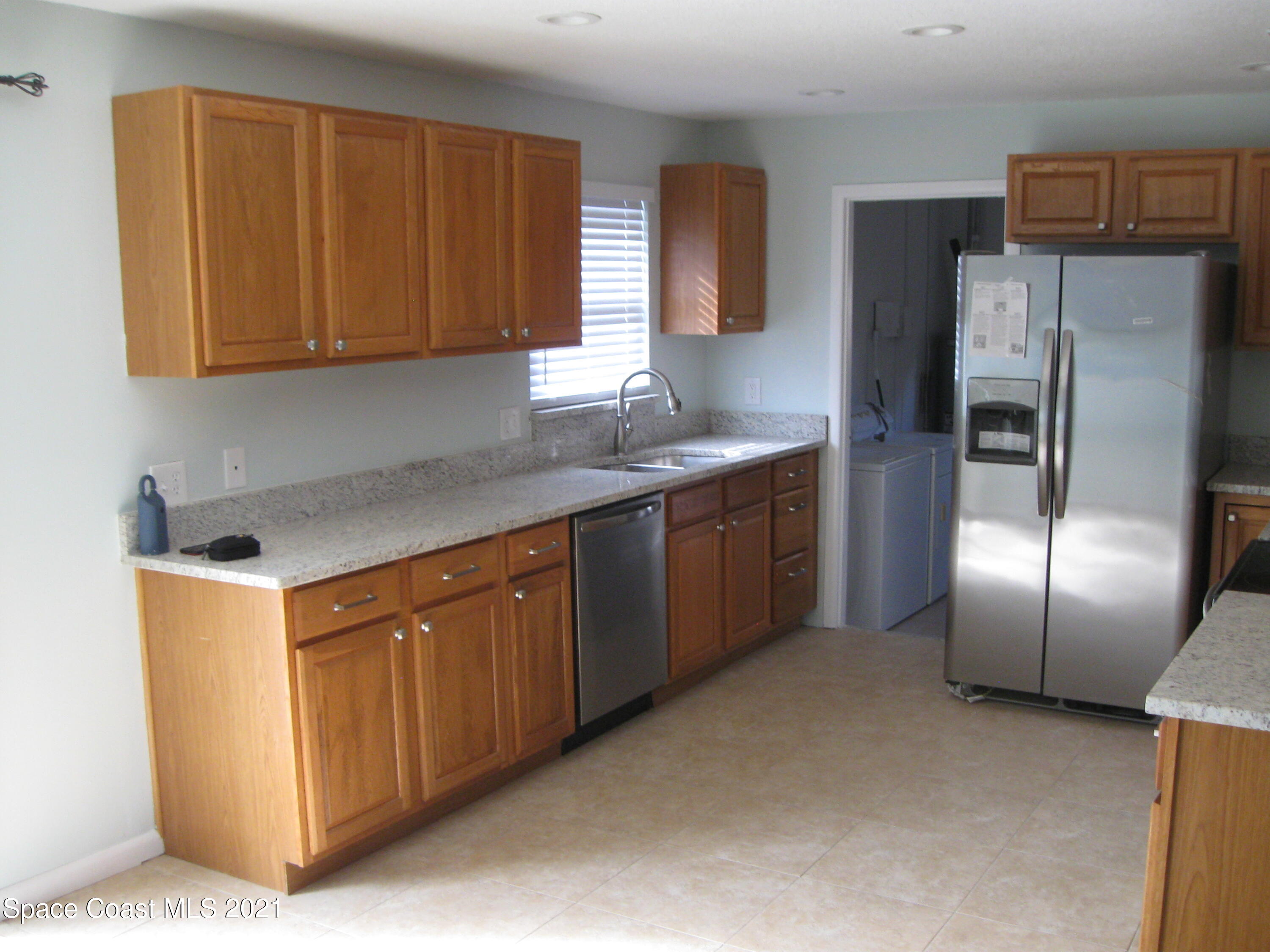 770 Sandgate Street Merritt Island, FL 32953 - Photo 6 of 22 a kitchen with stainless steel appliances granite countertop a refrigerator a sink a stove with wooden cabinets