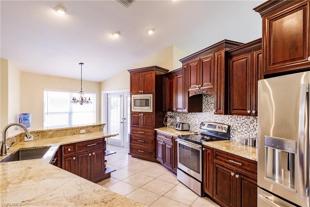 3881 Packinghouse Road Alva, FL 33920 - Photo 11 of 35 a large kitchen with stainless steel appliances granite countertop a stove refrigerator and cabinets