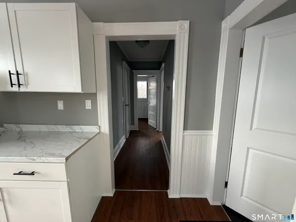 a view of a hallway with wooden floor and cabinets