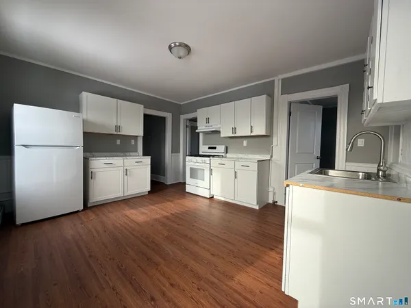 a kitchen with a sink a stove a refrigerator and white cabinets
