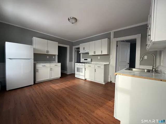 a kitchen with a sink a stove a refrigerator and white cabinets