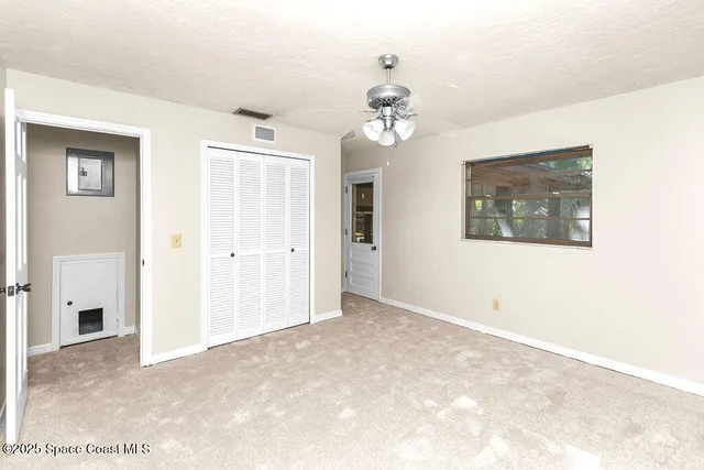 an empty room with windows and fan