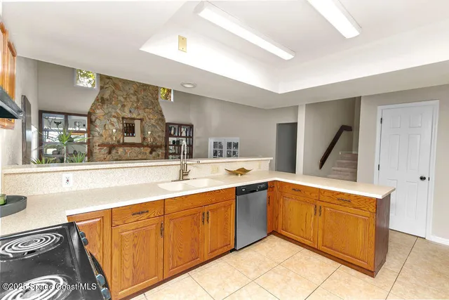 a kitchen with stainless steel appliances kitchen island granite countertop a refrigerator a sink dishwasher stove and oven with wooden cabinets