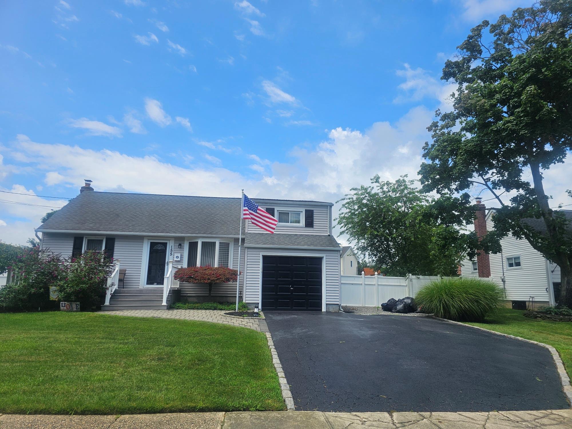 View of front facade featuring driveway and roof with shingles
