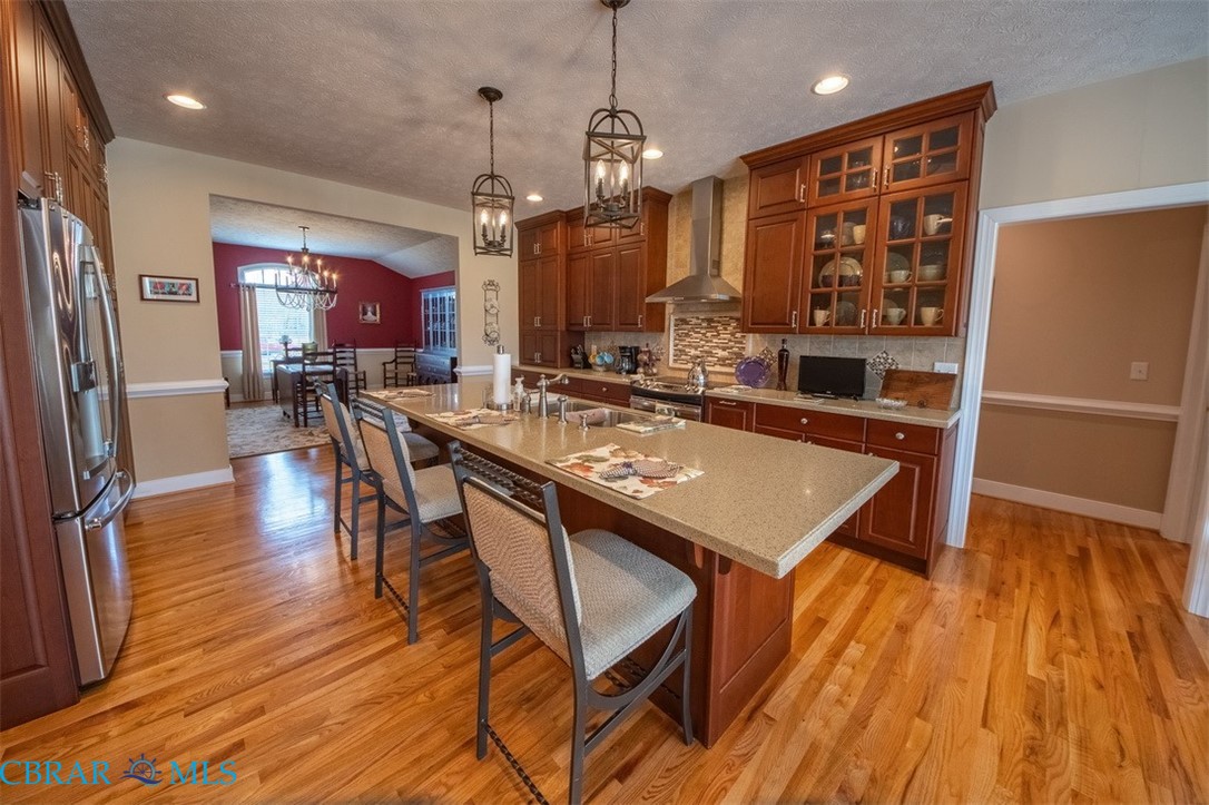120 North Shore Road Locust Hill, VA 23092 - Photo 28 of 39 Kitchen with a breakfast bar area, a kitchen island with sink, stainless steel appliances, light wood-style floors, and glass insert cabinets