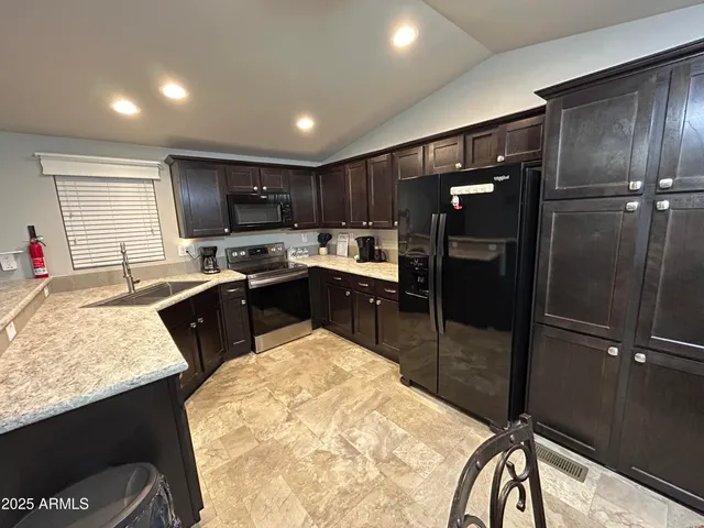 a kitchen with stainless steel appliances granite countertop a sink refrigerator and cabinets