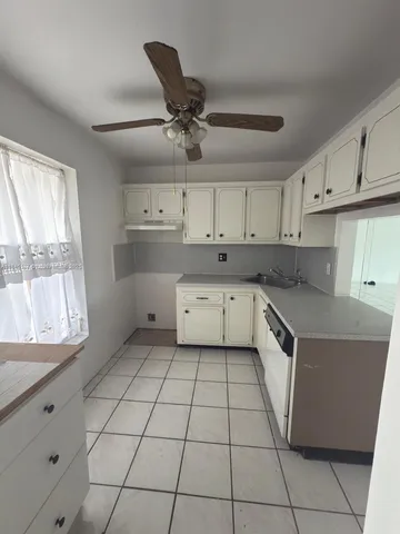a kitchen with a sink a stove cabinets and a window
